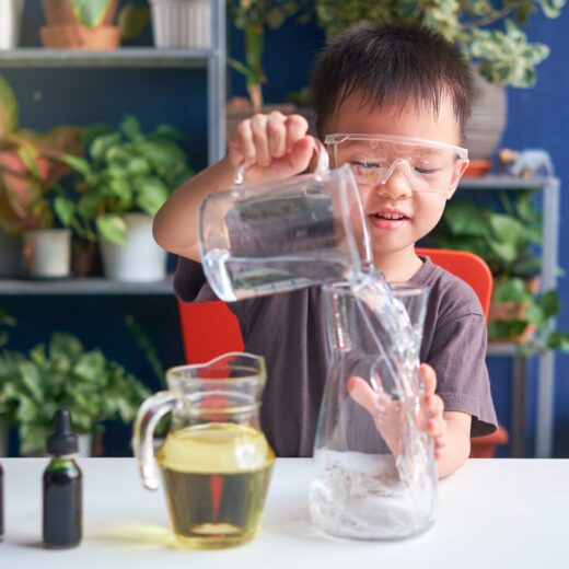 A young boy is pouring liquid into a glass.